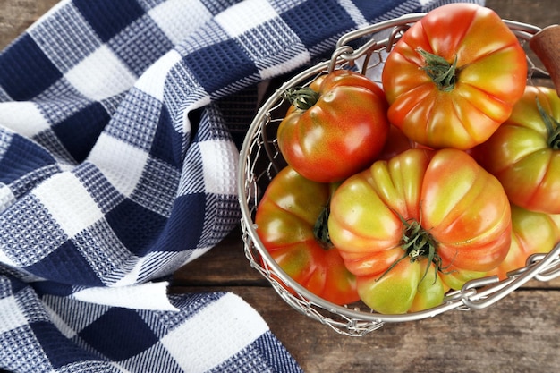 Green tomatoes in basket on table close up