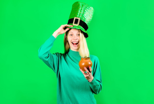 Photo green top hat blonde girl in leprechaun costume holds pot with gold leprechaun pot with gold green