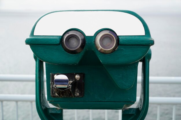 Green tourist binocular on coins and defocused sea on second plan