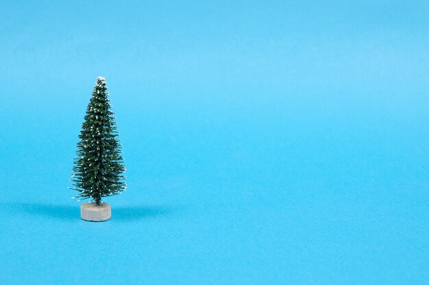 Green toy Christmas tree on a blue textured