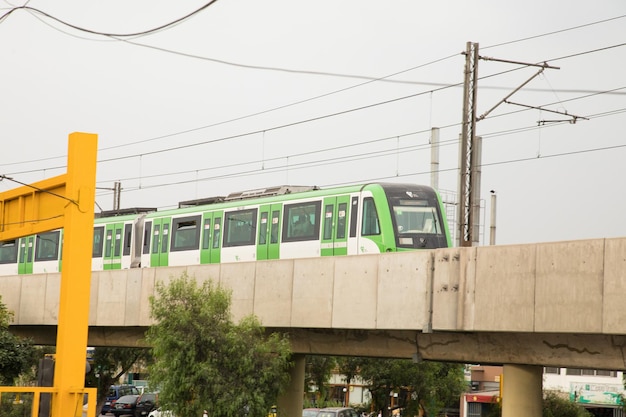 A green train on a bridge with a white sign that says metro on it.