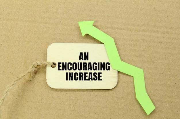 a green upward arrow and a wooden tag with the words an encouraging increase