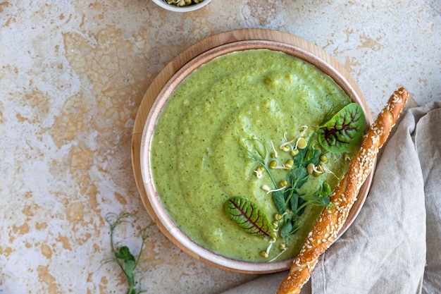 Photo green vegetable cream soup with micro greens and breadstick vegan soup puree of green vegetables