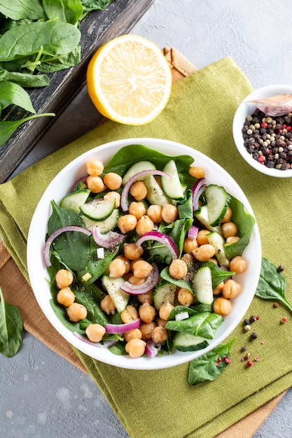 Green vegetable salad with chickpea spinach cucumber red onions and greens on a light slate stone or concrete background Top view