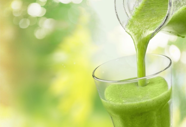 Green vegetable smoothie pouring in glass