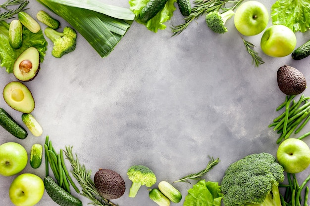 Green vegetables avocado broccoli beans leek and fresh apple on grey stone