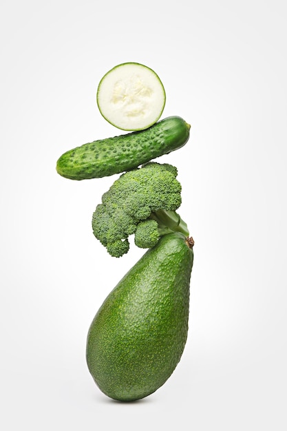 Green vegetables balancing on a white isolated background Ingredients for food preparation The concept of diet and vegetarianism