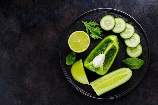 暗い背景に緑の野菜や果物。黒いプレート上の緑のダイエット食品。健康食品。上面図。コピースペース