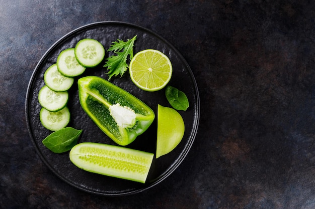 暗い背景に緑の野菜や果物。黒いプレート上の緑のダイエット食品。健康食品。上面図。コピースペース