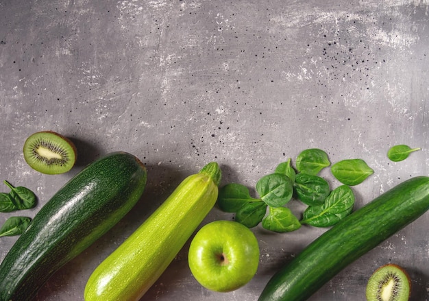 Green vegetables and fruits on a gray concrete background