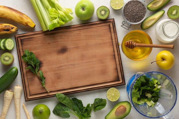 Green vegetables and fruits for a green detox drink on a light table, top view