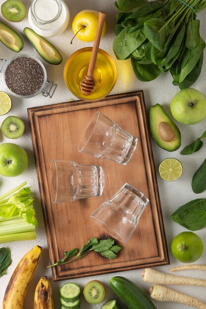 Green vegetables and fruits for a green detox drink on a light table, top view