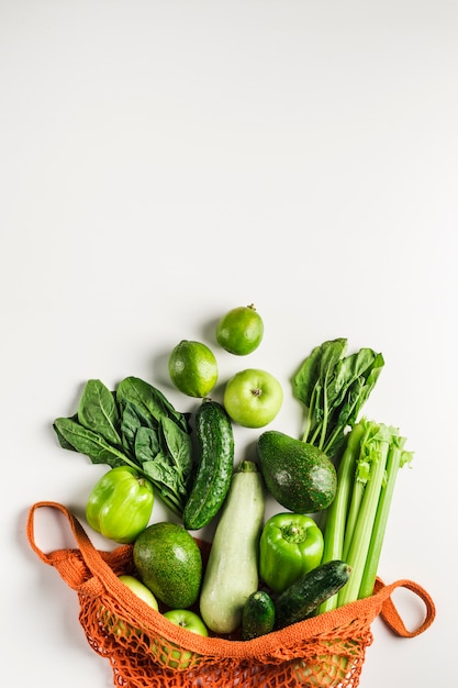 Green vegetables and fruits in orange string bag