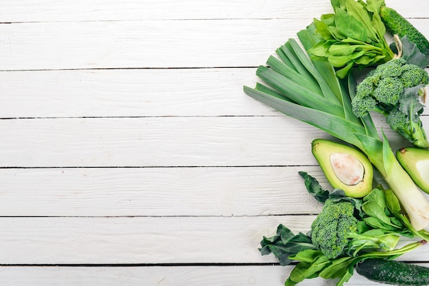 Green vegetables and fruits On a white wooden background Healthy food Top view Copy space