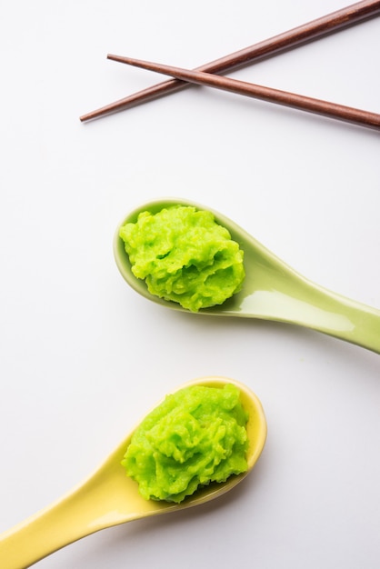 Salsa o pasta di wasabi verde in una ciotola, con le bacchette o un cucchiaio su uno sfondo colorato. messa a fuoco selettiva