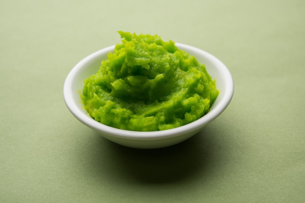 Salsa o pasta di wasabi verde in una ciotola, con le bacchette o un cucchiaio su uno sfondo colorato. messa a fuoco selettiva