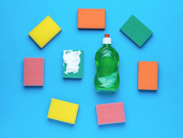 Gel di lavaggio verde e un set di spugne in schiuma su sfondo blu concetto minimo di lavaggio e pulizia