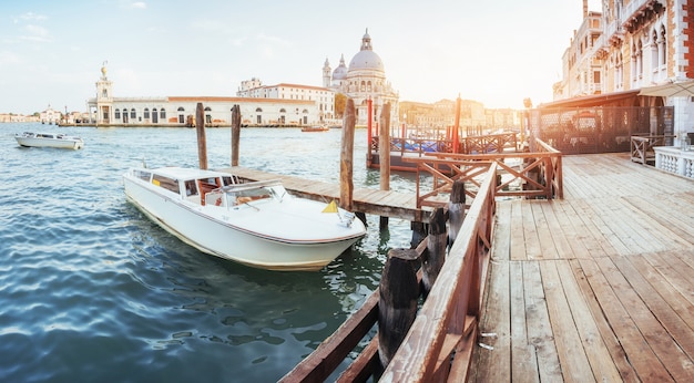 Canale idrico verde con le gondole e le facciate variopinte di vecchie costruzioni medievali al sole a venezia