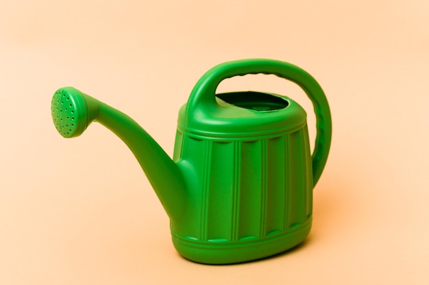 Green watering can isolated on beige background