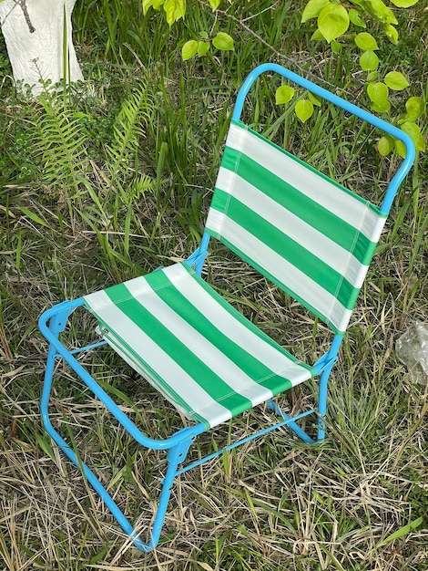 A green and white striped chair is sitting in the grass.