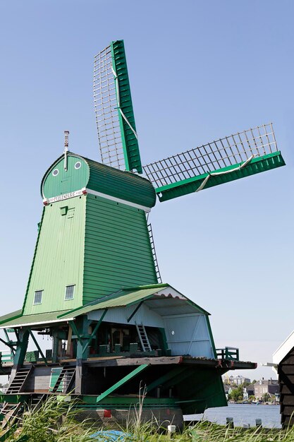 Фото Зеленая ветряная мельница zaanse schans на фоне голубого неба нидерланды