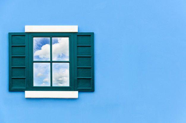 Casa finestra verde aperta per riflettere il cielo estivo e nuvola bianca su uno specchio sulla parete blu all'esterno, vecchia cornice di finestre in legno di casa italia classico stile vintage copia spazio per lo sfondo