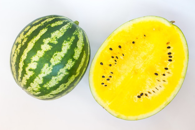 Photo green with white stripes watermelon. half of yellow watermelon.