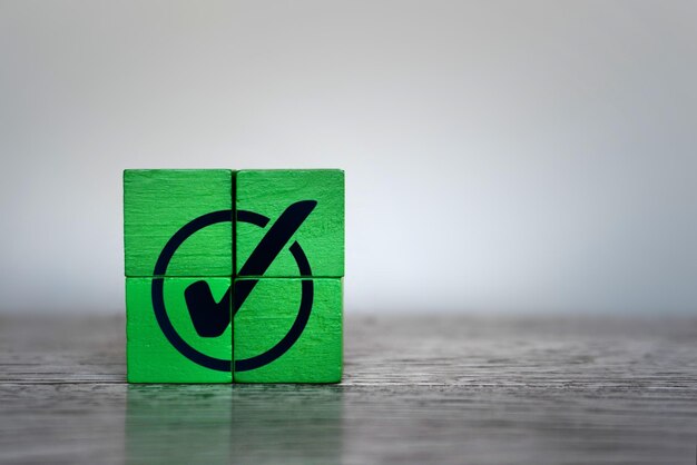 Green wooden cubes with checkmark icon Corporate regulatory compliance achievement completed task