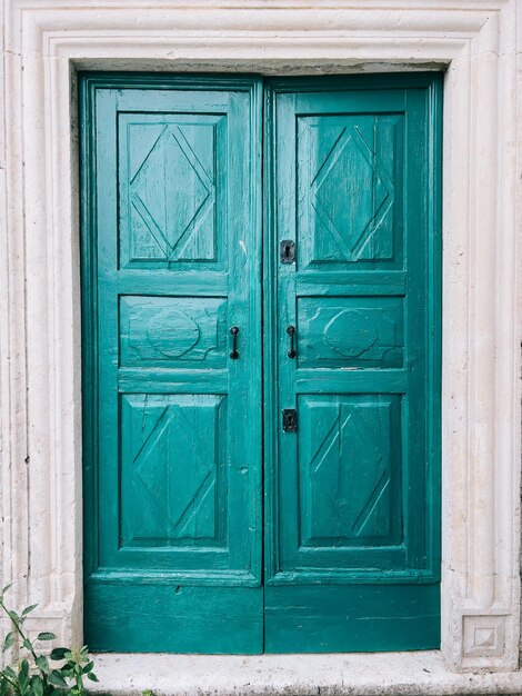 Foto porta di legno verde con cornice in pietra bianca