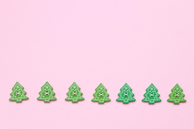 Green wooden figures in the form of Christmas Tree on a pink background