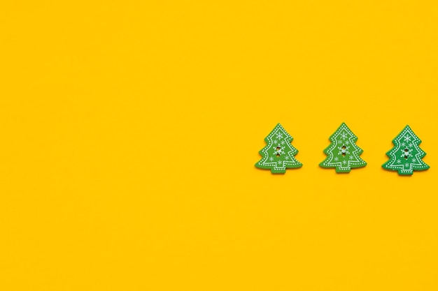 Figure in legno verde a forma di albero di natale su sfondo giallo concetto di capodanno