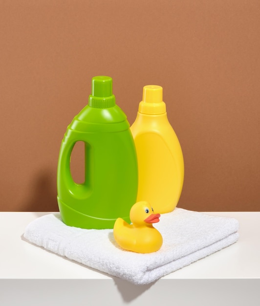 A green and yellow bottle of laundry detergent and a yellow duck on a white clean towel