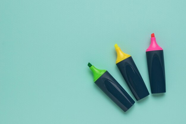 Green yellow and red marker on a light blue background Flat lay