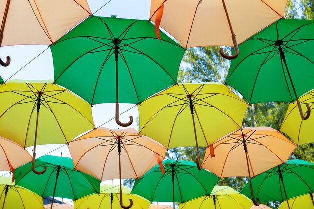 Green and yellow umbrellas hanging above city streets. Colorful umbrellas in sky.