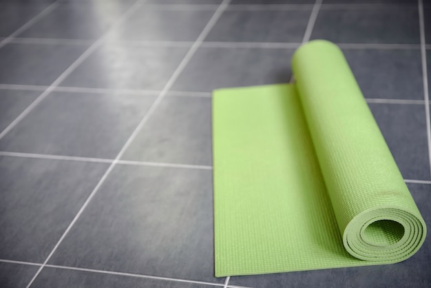 Green yoga mat on gray tile floor 