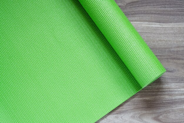 Green yoga mat on a wooden background