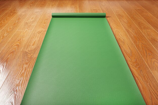 Green Yoga mat on wooden floor unfolded. Healthy lifestyle, fitness, sports. Top view.