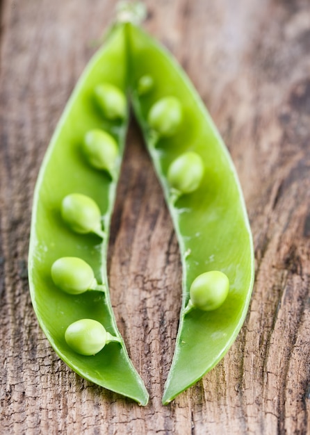 Photo green young green peas on a wooden background