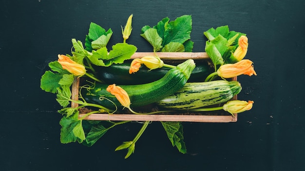 Green zucchini in a wooden box Fresh vegetables On a black wooden background Top view Copy space