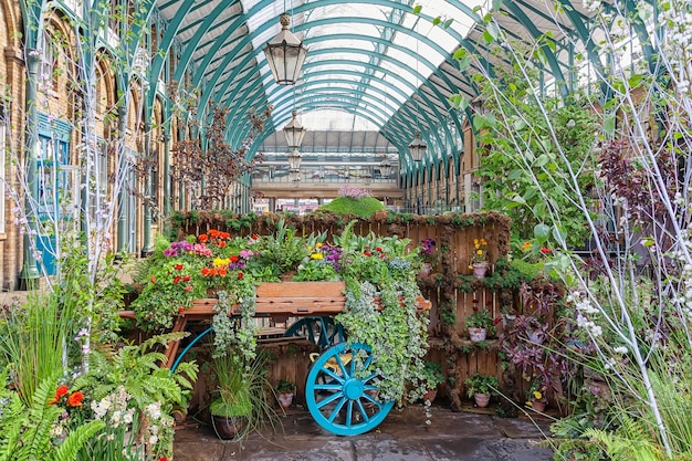花や植物でいっぱいのカートがある温室。