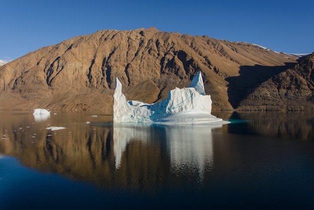 Гренландский пейзаж с красивыми цветными скалами и айсбергом.