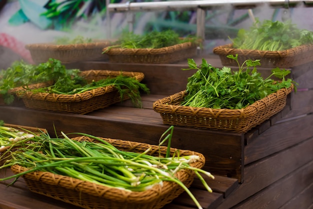 Greens on the counter of the storeDill and parsley on a wooden table blown with moisturizing steam