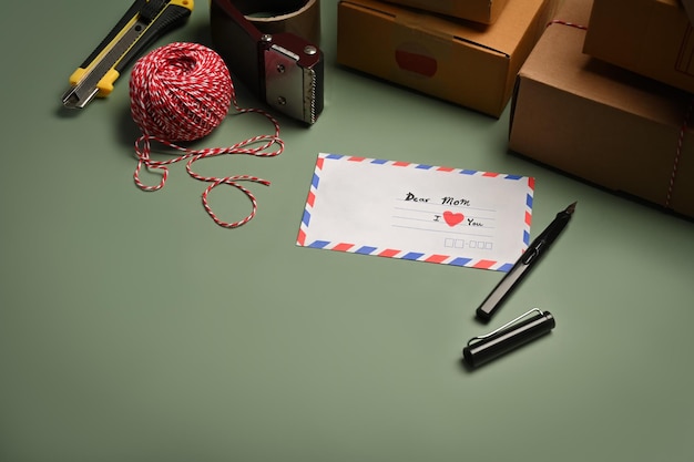 Картонные коробки для поздравительных открыток, корреспонденция, конверт, лента и клубки веревки на зеленом фоне
