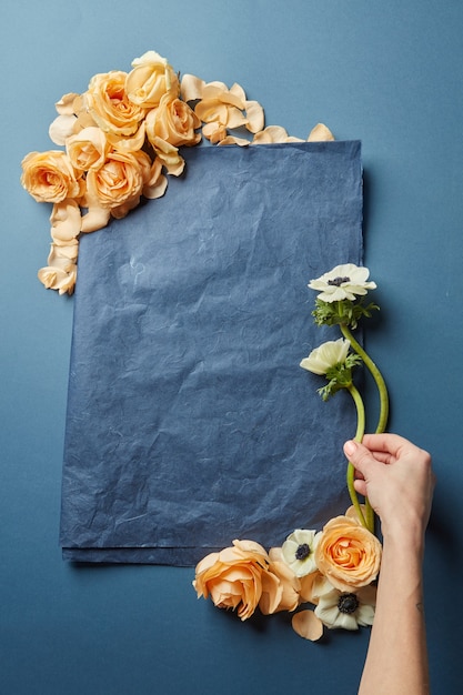 Greeting card decorated with orange roses. Female's hand decorating wedding card composition.