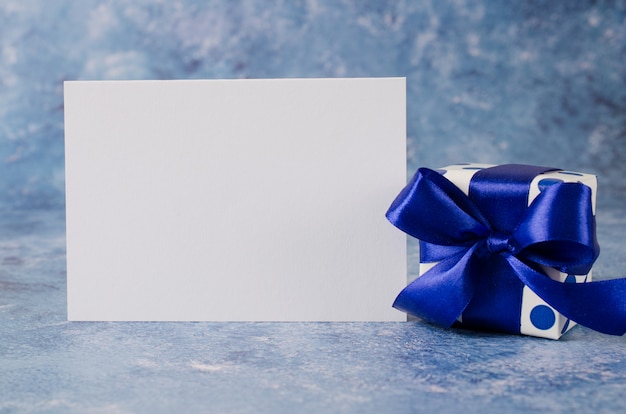 Greeting card for Father's Day or Birthday. Gift box with blank white paper on blue background.