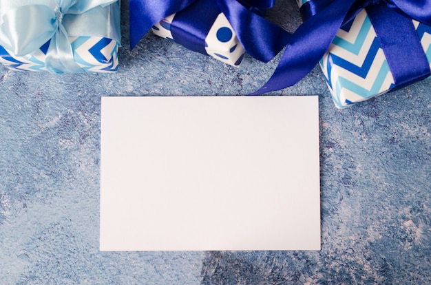 Фото Открытка на день отца или день рождения. подарочная коробка с пустой белой бумаги на синем фоне.