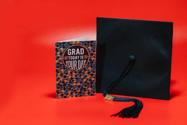 Greeting Card and Graduation Cap on Red Surface Stock Photo