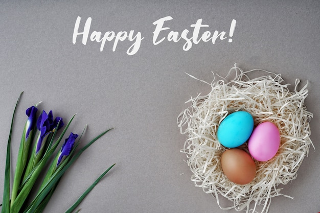 Greeting card happy easter. Colored eggs and nest, iris flowers. Good concept.