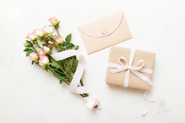 Greeting card mockup with copy space pink ribbon and roses flowers on colored table background Flat lay top view mother day holiday concept