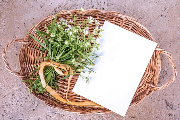 Greeting card on mothers day bouquet of wild flowers and blank postcard on wicker tray